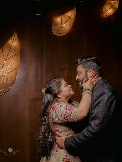 A sweet, intimate moment between a couple during their engagement event. The warm, ambient lighting from the leaf-shaped fixtures adds a unique and cozy atmosphere.