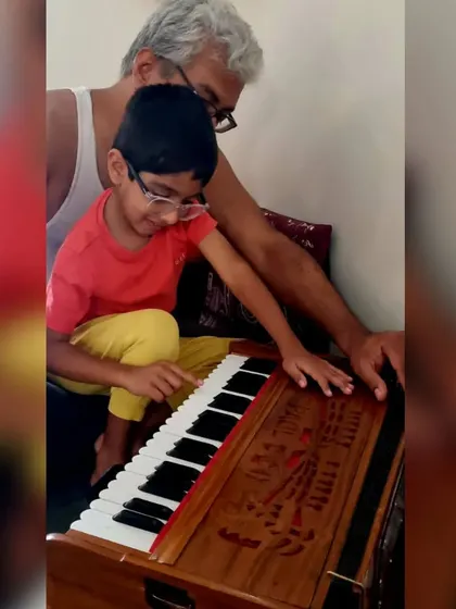 A grandfather passing on his love for music, guiding his grandson's fingers on the harmonium. Our sessions welcome every generation, creating a true family learning environment.