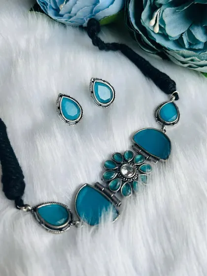 Another view of the beautiful blue stone choker set against a floral background, highlighting its serene and elegant design.