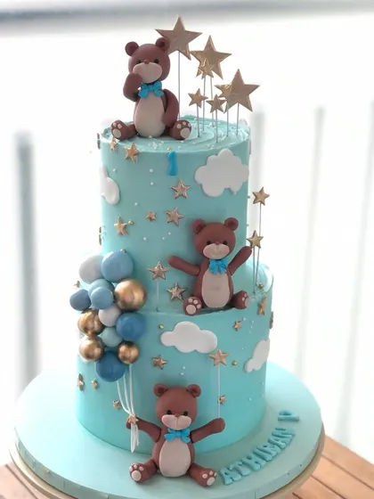 A dreamy two-tiered teddy bear cake with a "twinkle twinkle little star" theme, perfect for a first birthday.