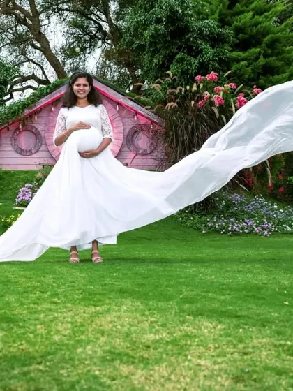 This white flying gown is perfect for an angelic and serene maternity photoshoot. The extra-long trail creates a stunning visual against the lush green grass.
