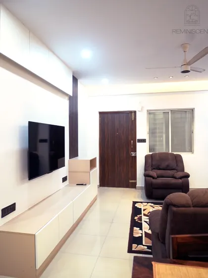 A minimalist living room with a long, low-profile TV unit in white and wood tones. The clean lines and uncluttered design create a sense of calm and space.