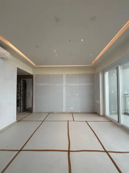 A work-in-progress shot of a living room. At this stage, the structural elements and electrical layouts are in place, forming the "bones" of the space before the final finishes are applied.