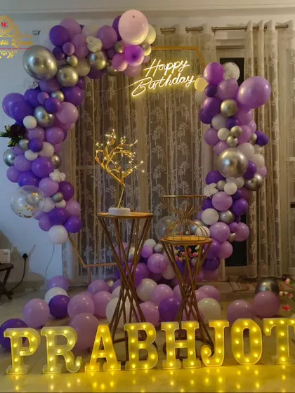 A birthday decoration with a purple and silver balloon arrangement on a hexagonal frame.