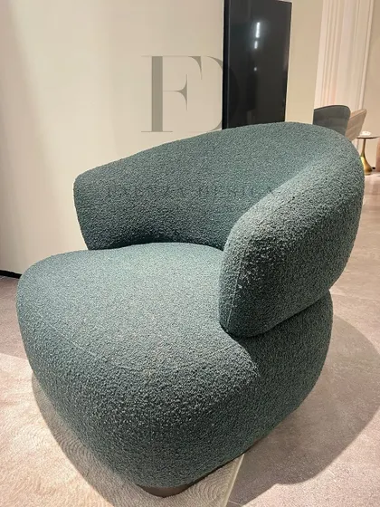 A modern armchair in a green bouclé fabric. The chair's unique, organic shape and textured upholstery make it a standout piece that adds both comfort and sculptural interest.