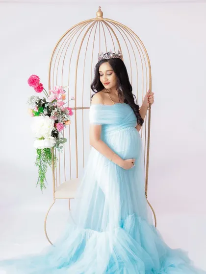 A duplicate of image 359, this fairytale portrait in a light blue gown with a golden birdcage chair is fit for a princess.