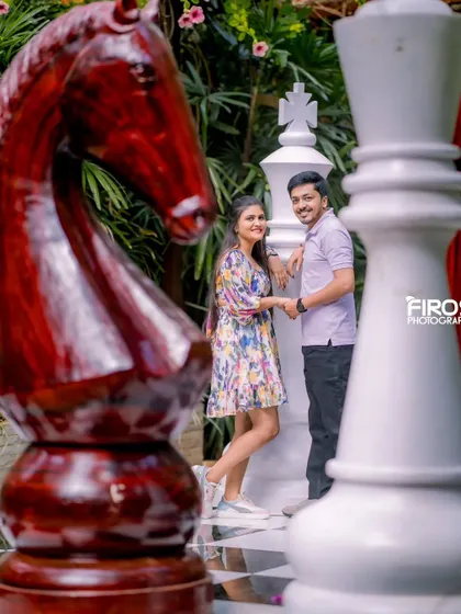 A creative shot on the giant chessboard, using the chess pieces to frame the couple. This is a great example of a unique and artistic pre-wedding photo.