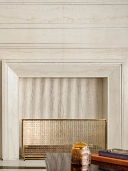 A close-up of the fireplace clad in white Ondulutu stone. The stepped, geometric design is a modern interpretation of a classic form, showcasing our attention to detail and ability to create cohesive architectural elements.