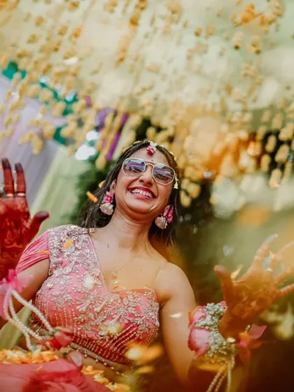 A beautiful, artistic shot of the bride with her henna-covered hands, seen through a shower of flower petals.