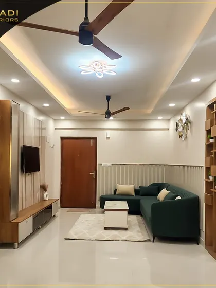 A modern living room with a comfortable dark green sectional sofa, a minimalist TV unit, and a wooden partition that provides a subtle separation from the adjoining kitchen area.