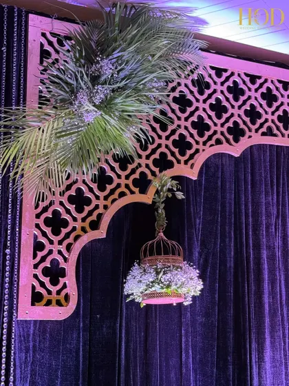 A close-up of the hanging birdcage filled with white flowers, a unique and charming detail for a sangeet or reception stage.