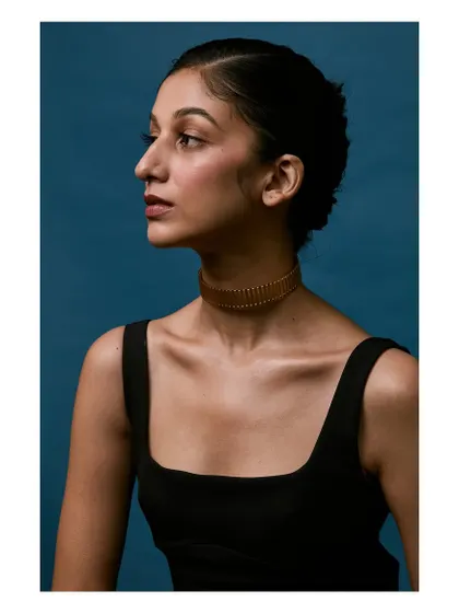 A profile shot highlighting a beautiful gold choker. This angle is perfect for showing how a piece of jewelry sits on the neck and complements the wearer's features.