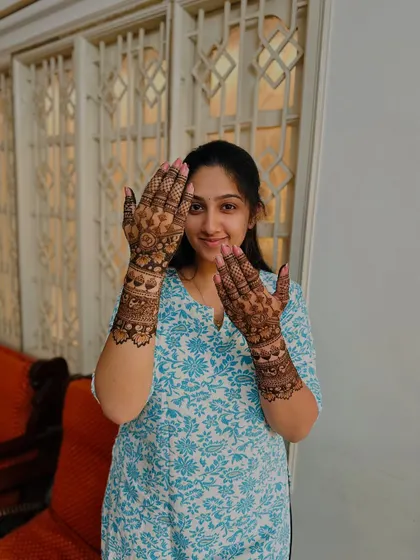 The bride proudly displays her detailed mehndi, a smile on her face.