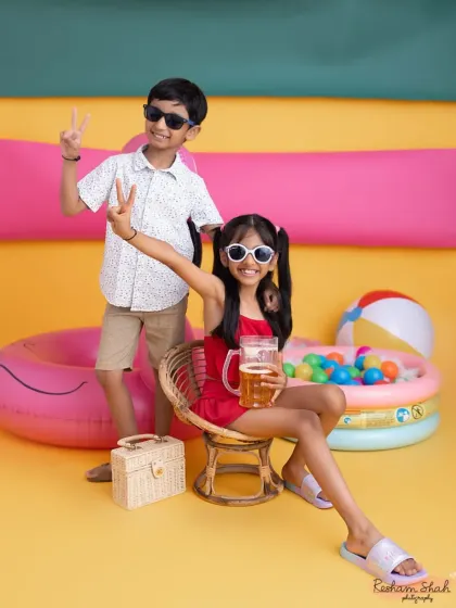 Peace out! These siblings are having a blast at their studio beach party. Themed shoots are a great way to capture sibling fun.
