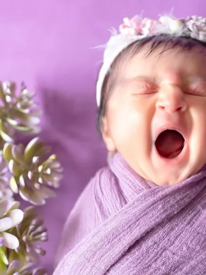 I love capturing those precious yawns! This little one, wrapped in lavender, lets out a big yawn, showing a real and adorable moment.