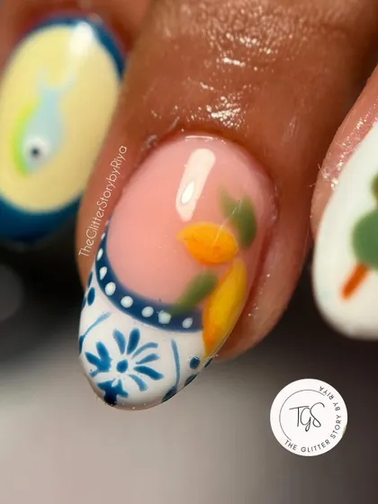 A close-up of a hand-painted nail inspired by Italian summer, featuring a lemon design on a Portuguese tile-style base.