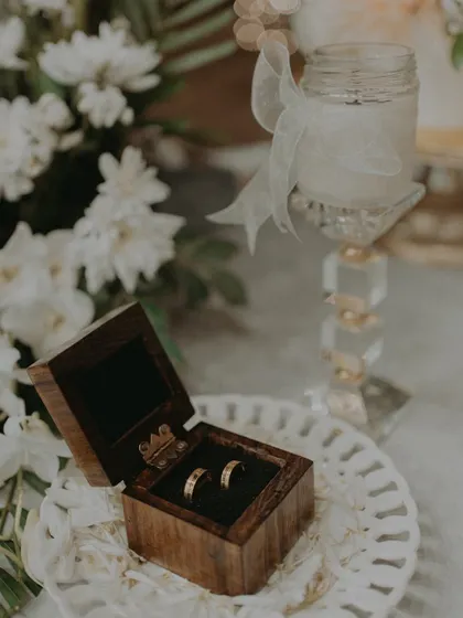 An aesthetic shot of the engagement rings nestled in their box, placed on a decorative plate with flowers.