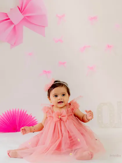 A sweet, seated portrait of the birthday girl in her beautiful pink dress, surrounded by bows and fans. Cuteness overload!