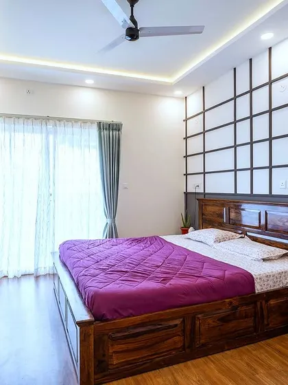 The master bedroom in the 'Blackwood' project, featuring a rich wooden bed, a geometric accent wall, and a floating TV console for a clean, contemporary feel.