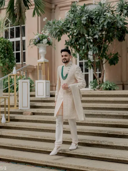 The groom looking regal as he descends a grand staircase at the wedding venue.