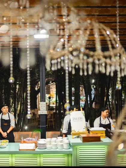 A live Jalebi station set up under elegant chandeliers at a wedding event.