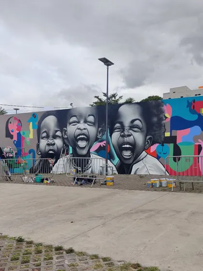 The mural in context with other artworks at the festival, showing a blend of our abstract style with hyperrealism.