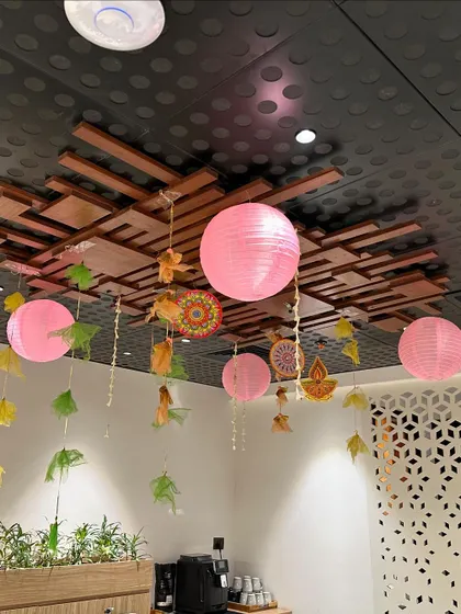 Modern Diwali office decor using pink paper lanterns and hanging leaf cutouts for a contemporary festive look.