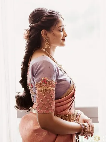 A side profile of the bride, showcasing her intricate braided hairstyle and the soft glow of her makeup.