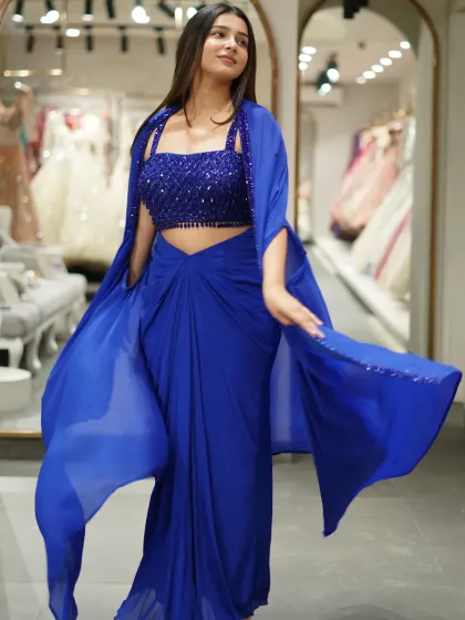 This royal blue dhoti-saree set with a matching cape is for the girl who loves to fuse modern with traditional. The beaded crop top and flowing cape make it a comfortable yet drop-dead gorgeous outfit for a cocktail party.