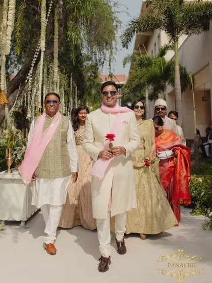 The groom's procession, with his family walking alongside him, holding a single red rose.