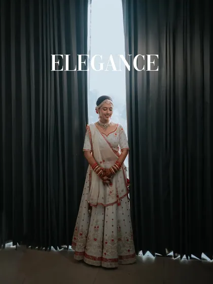 Elegance. A stunning full-length portrait of the bride against a dark curtain, the simple composition highlighting her beautiful white lehenga.