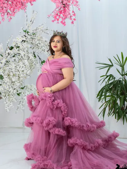 A beautiful portrait against a backdrop of pink and white blossoms. The mom-to-be wears a multi-layered pink gown, creating a soft, romantic, and textured image.