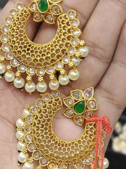 A pair of lightweight gold-look chandbalis with pearl drops. The jaali (net) work makes them light and comfortable to wear for long hours.