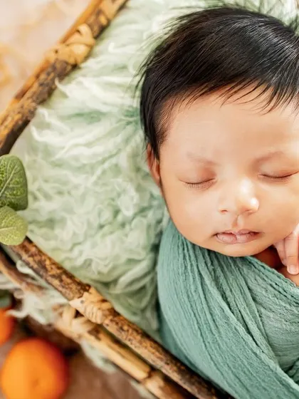 A pop of color with this citrus-themed newborn setup. Using natural elements like these small oranges adds a fresh and unique touch to the classic basket pose.