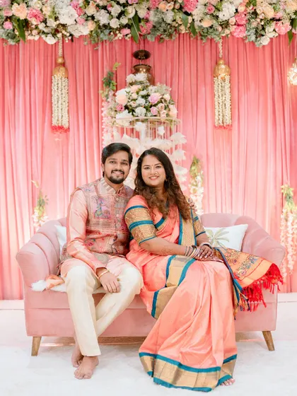 A classic seated portrait of the couple against their beautiful engagement ceremony backdrop. The pastel colors and floral decor create a lovely setting.