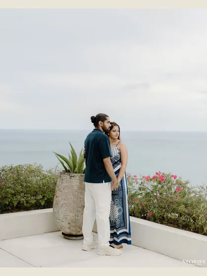 A quiet, contemplative portrait of the couple standing on a balcony, looking out at the vast ocean together.