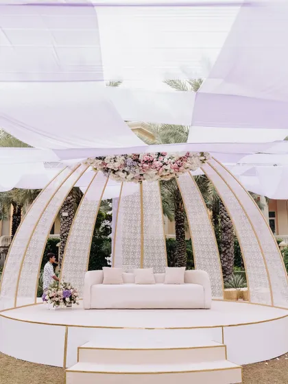 A modern, dome-shaped stage structure, elegantly decorated with a floral crest, providing a chic and sophisticated backdrop.