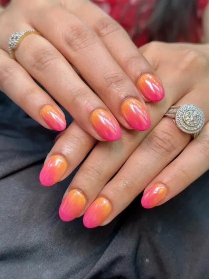A final look at the pink and orange chrome ombre nails, showing how perfectly they complement the client's skin tone and jewelry.