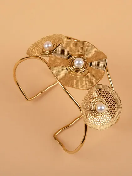 An angled shot of the gold floral cuff bracelet.