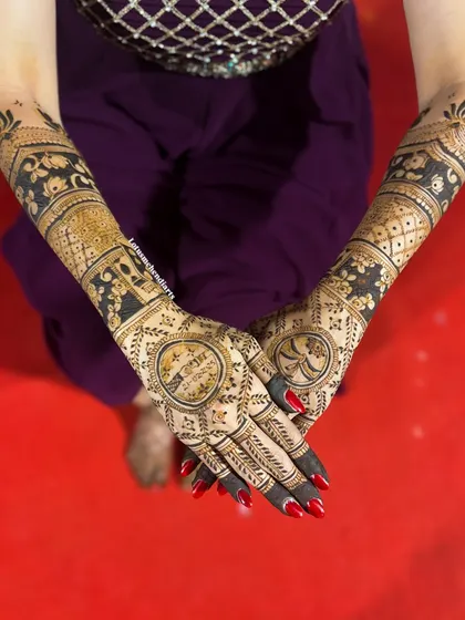 The back of the hands for Rajalakshmi's bridal mehendi, featuring initial monograms inside a beautiful mandala, surrounded by peacock and lotus motifs.