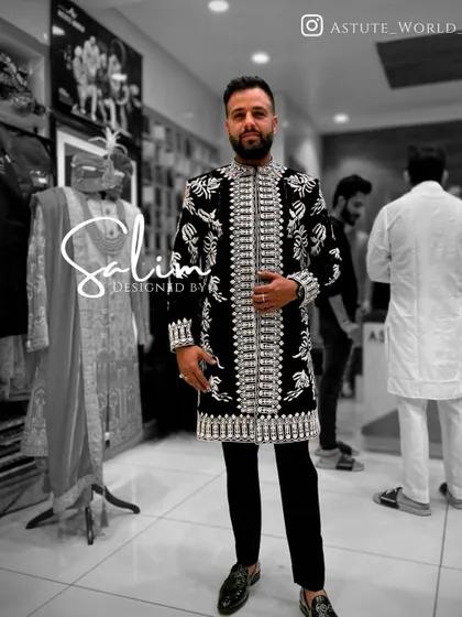 A client in a long black jacket with heavy, all-over silver embroidery, worn over black trousers. This creates a powerful, modern ethnic look.
