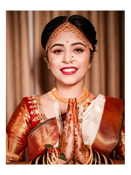 A beautiful close-up of the bride with her hands in a traditional 'namaste' greeting, her smile radiating warmth and happiness.