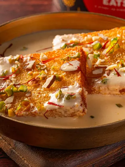 Shahi Tukda from Charcoal Eats, presented in a traditional brass bowl. The lighting highlights the glistening texture of the rabri and the crunch of the nuts, perfect for a Zomato or Swiggy menu.