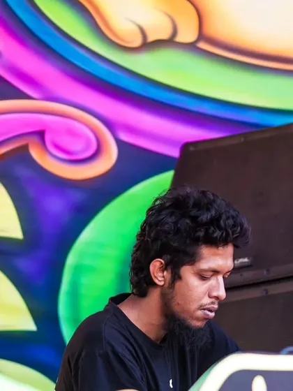 A close-up of a DJ concentrating on his music, with the vibrant colors of the stage art creating a striking contrast.