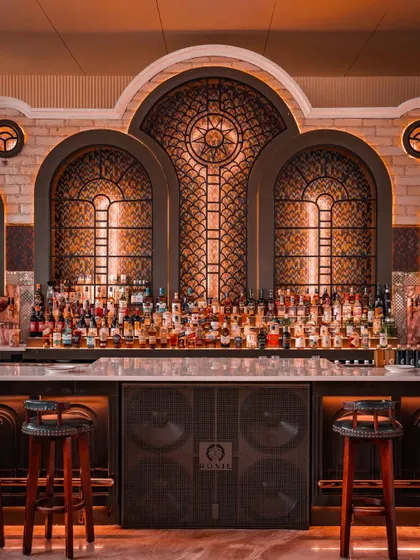 The main bar stands as a cathedral of spirits. The intricate woodwork, dramatic backlighting, and extensive collection make it a central and impressive feature for any event.
