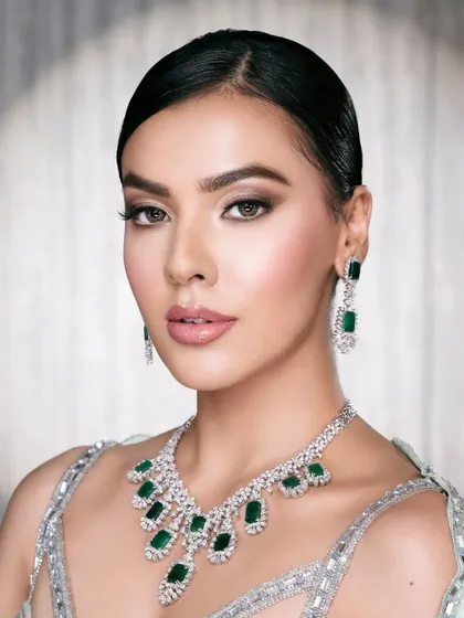 A clean, polished beauty shot that allows the model's natural beauty and the exquisite emerald jewelry to be the heroes.