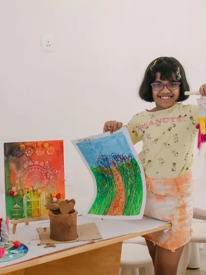 So many amazing projects from one of our camps! This young artist is surrounded by her creations, including a woven tapestry, a drawing, and a mixed-media piece.