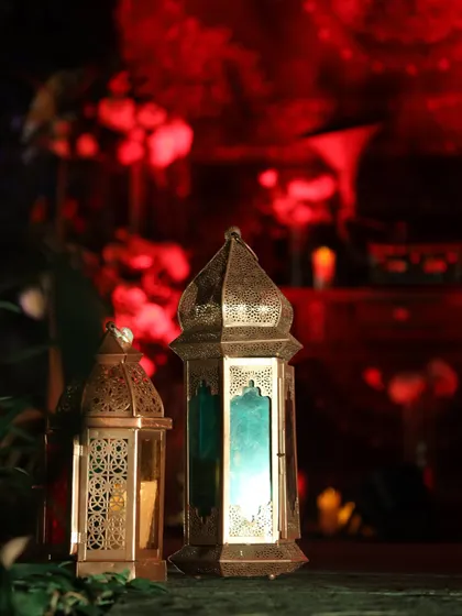 A pair of beautiful Moroccan lanterns cast a colorful glow, adding to the moody and romantic ambiance of an evening event.