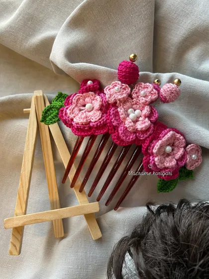 Our pink floral bun comb is displayed on a mini easel, highlighting it as a small piece of wearable art. The different shades of pink create a beautiful gradient effect.
