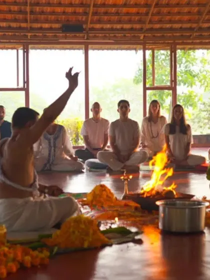 A priest raises his hand in blessing during a Puja fire ceremony. This powerful ritual marks a sacred beginning, filling the shala with positive energy and setting a clear intention for our shared journey.